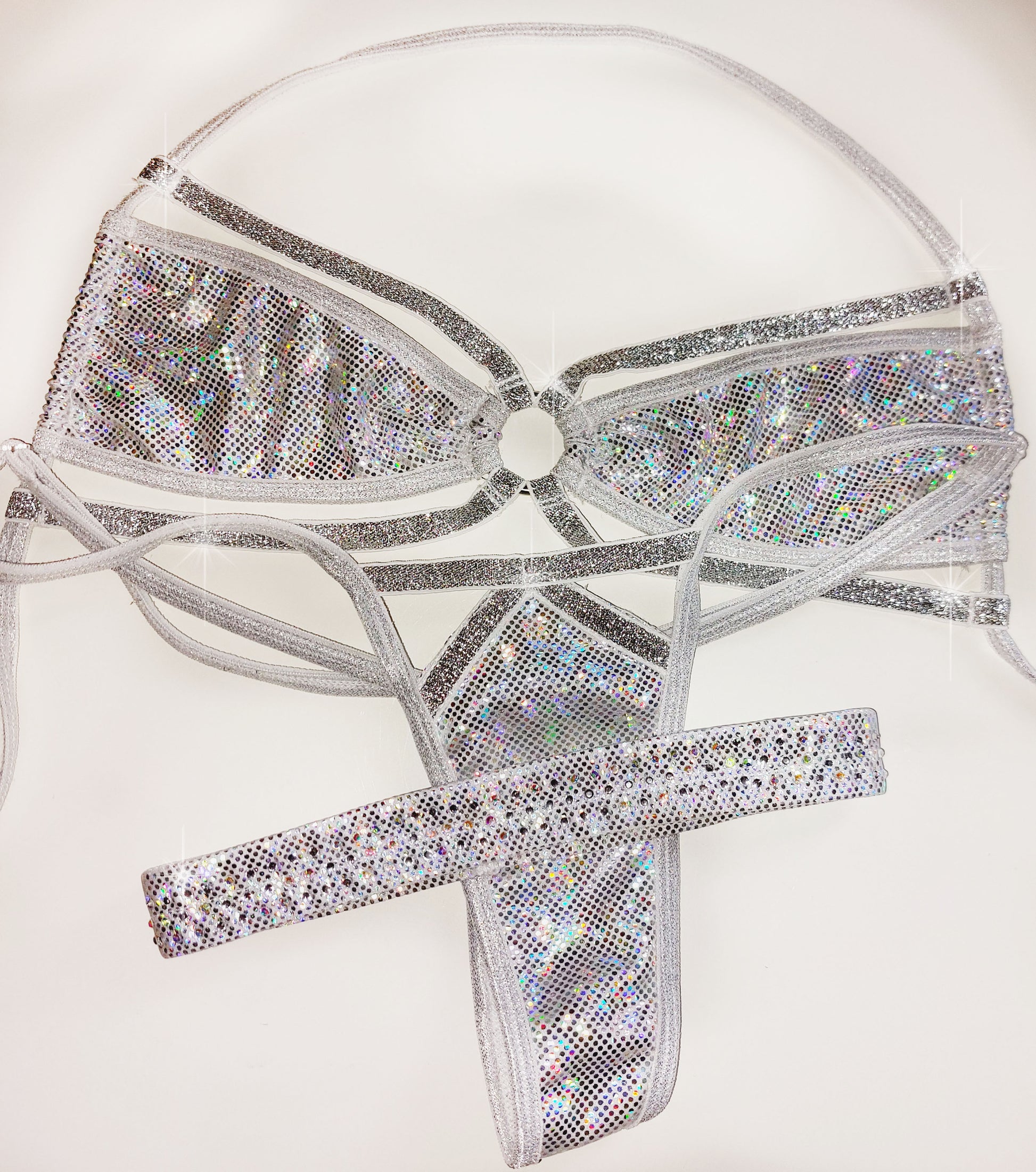 A three-piece white and silver hologram bikini costume set including a bra top, thong, and garter for leg, displayed on a plain white background.