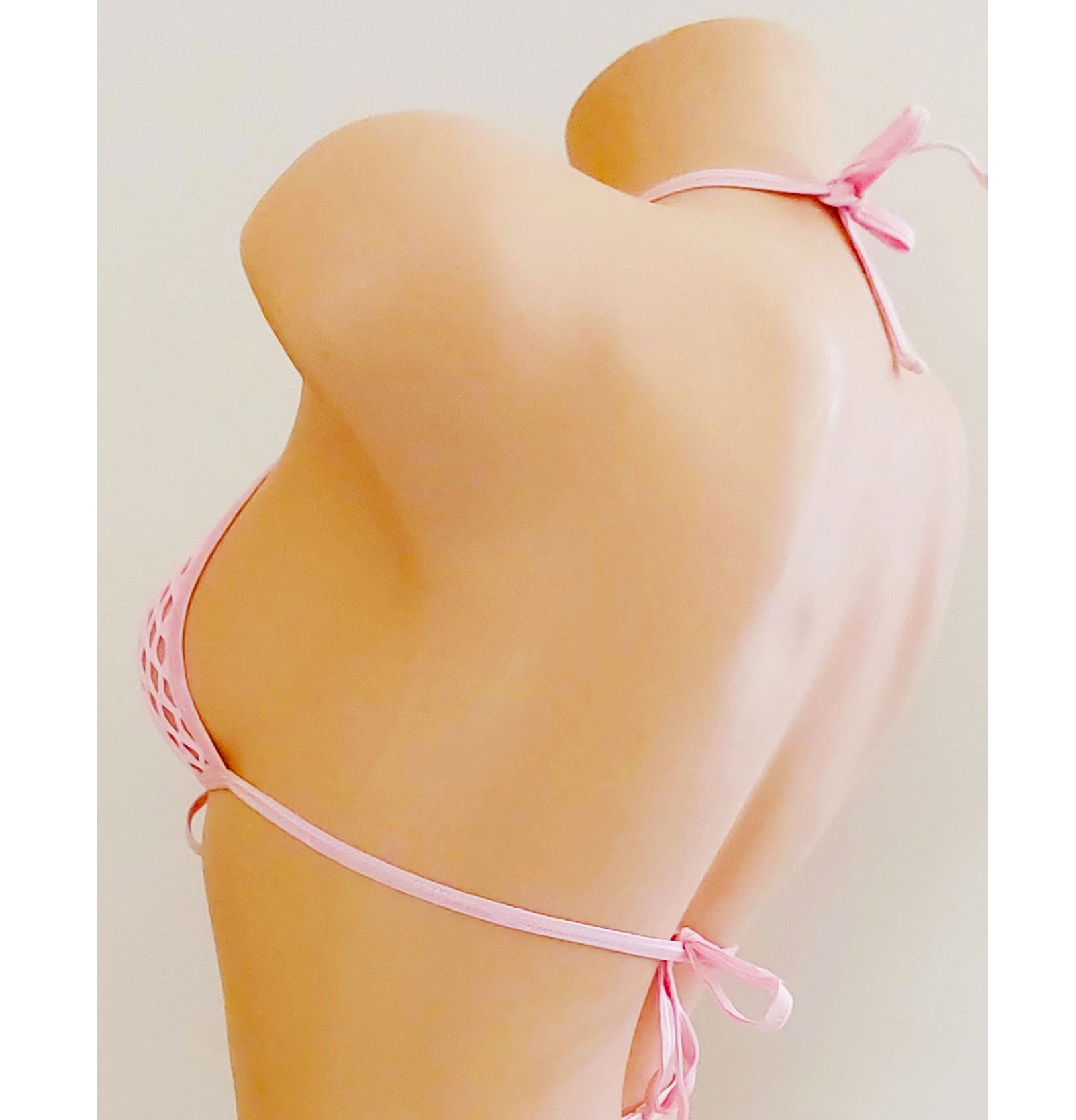 A light pink fishnet string bikini set displayed on a beige mannequin torso, showing the back view with adjustable waistband details against a plain light background.