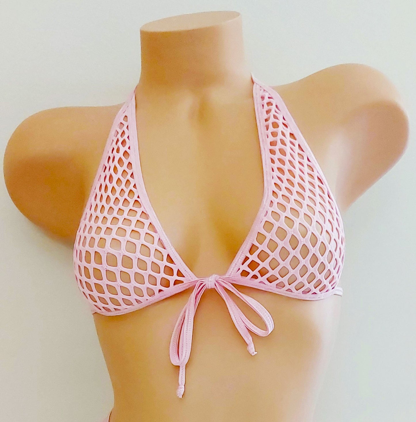 A two-piece pink fishnet bikini set displayed on a tan mannequin torso against a plain light background. The set includes a halter-style triangle top with a front tie and matching strappy low-rise bottoms with a mesh front panel.