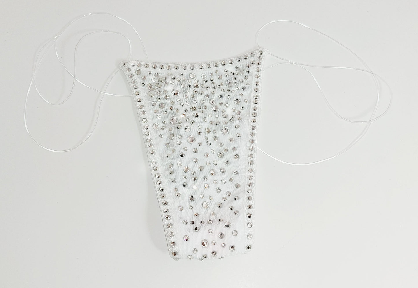 Product shot of White mesh invisible strap string bikini thong covered in diamond rhinestones on a white background.