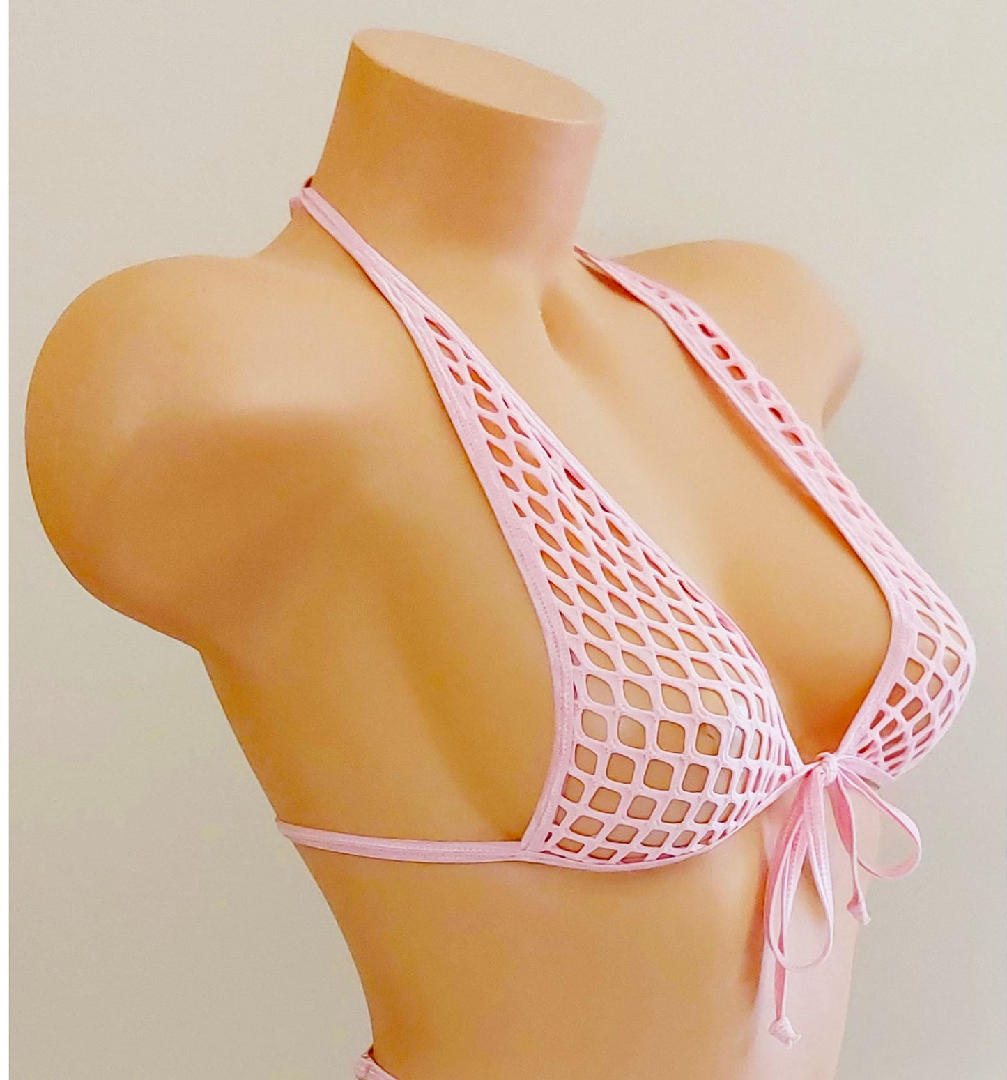 A pink stretch fishnet bikini set displayed on a tan mannequin torso against a plain light beige background.