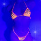 Black light shot of Sexy Orange Halloween bikini with black rhinestone spiderweb pattern on a curvy mannequin.