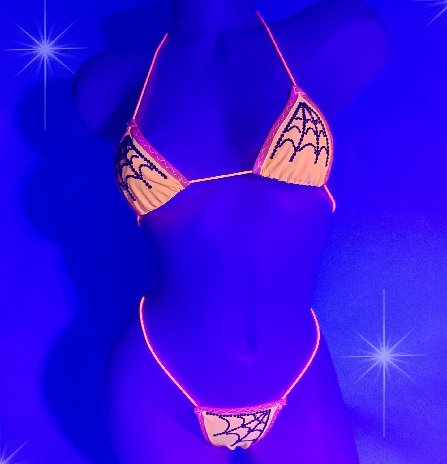 Black light shot of Sexy Orange Halloween bikini with black rhinestone spiderweb pattern on a curvy mannequin.