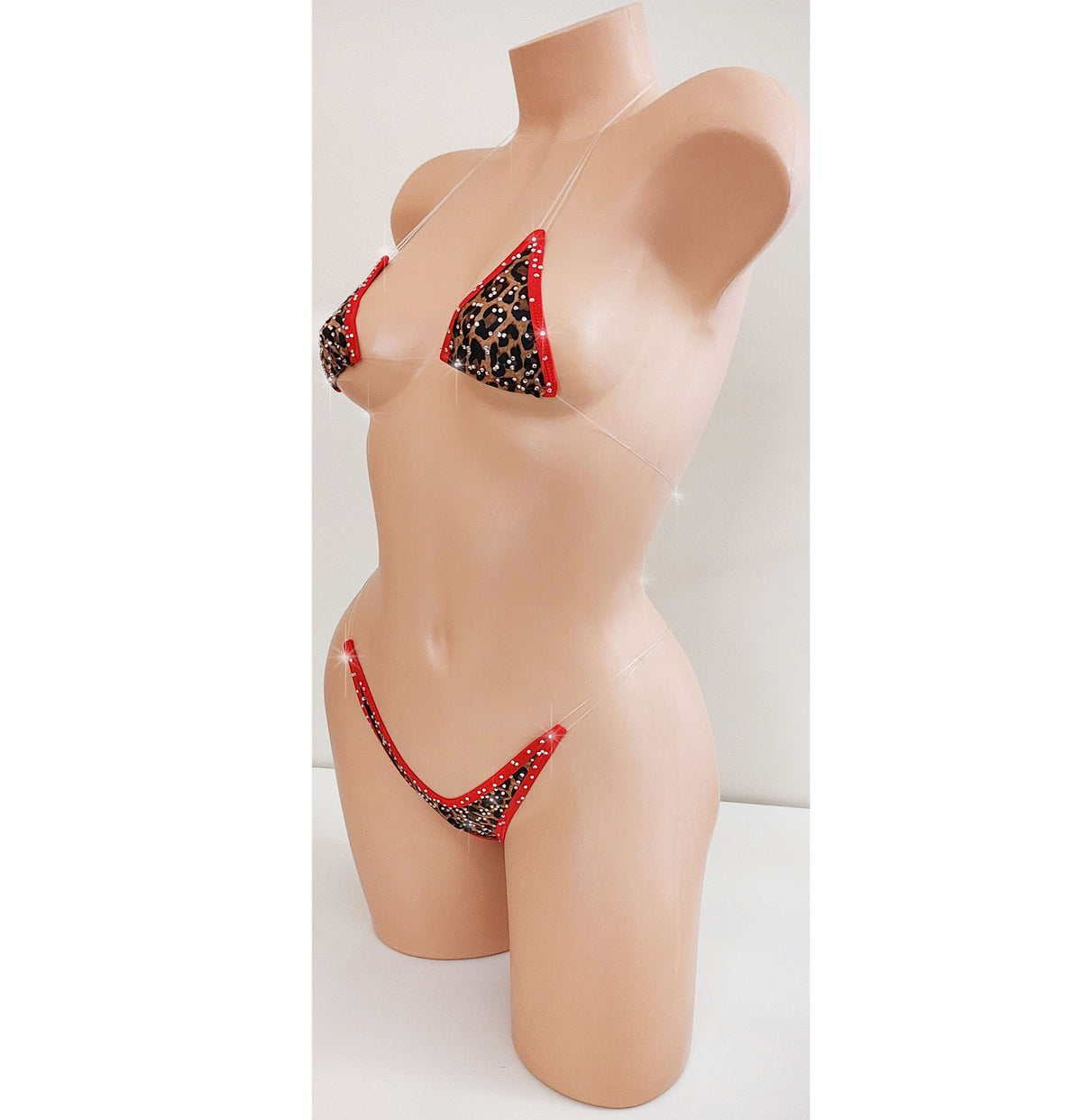 A two-piece bikini set displayed on a beige mannequin torso. The bikini features a black leopard print pattern with red trim and red side straps, set against a plain white background.