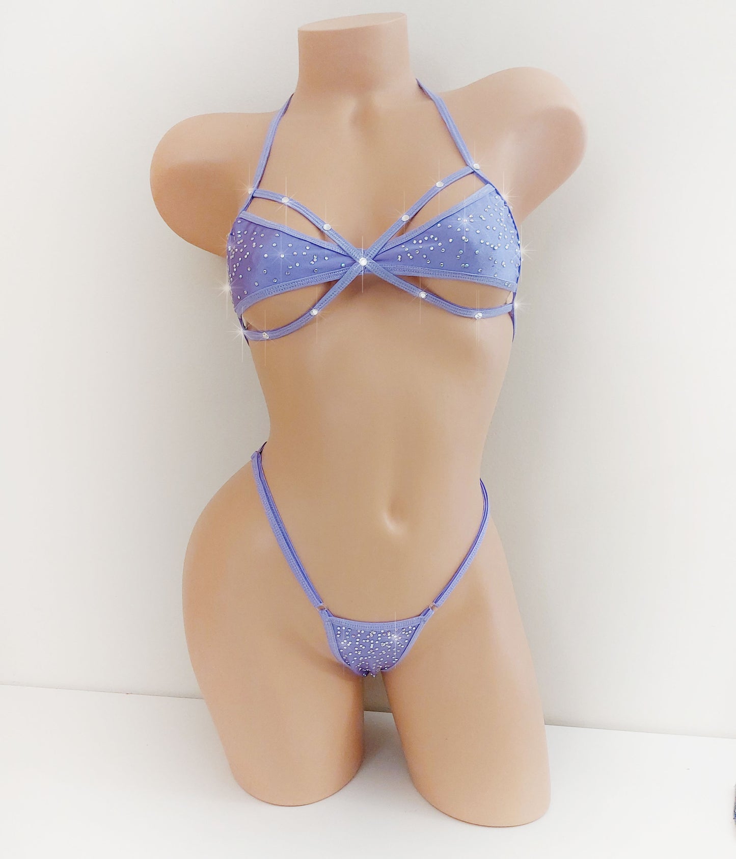A two-piece bikini set in light purple with silver glitter and rhinestone trim, displayed on a beige mannequin torso against a plain white background.