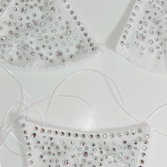 Video of Product of White mesh invisible strap string bikini thong covered in diamond rhinestones on a white background as well as displayed on a mannequin.