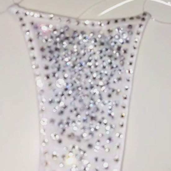 Video of a  sparkly white g-string thong covered in bedazzled rhinestones with clear elastic straps.